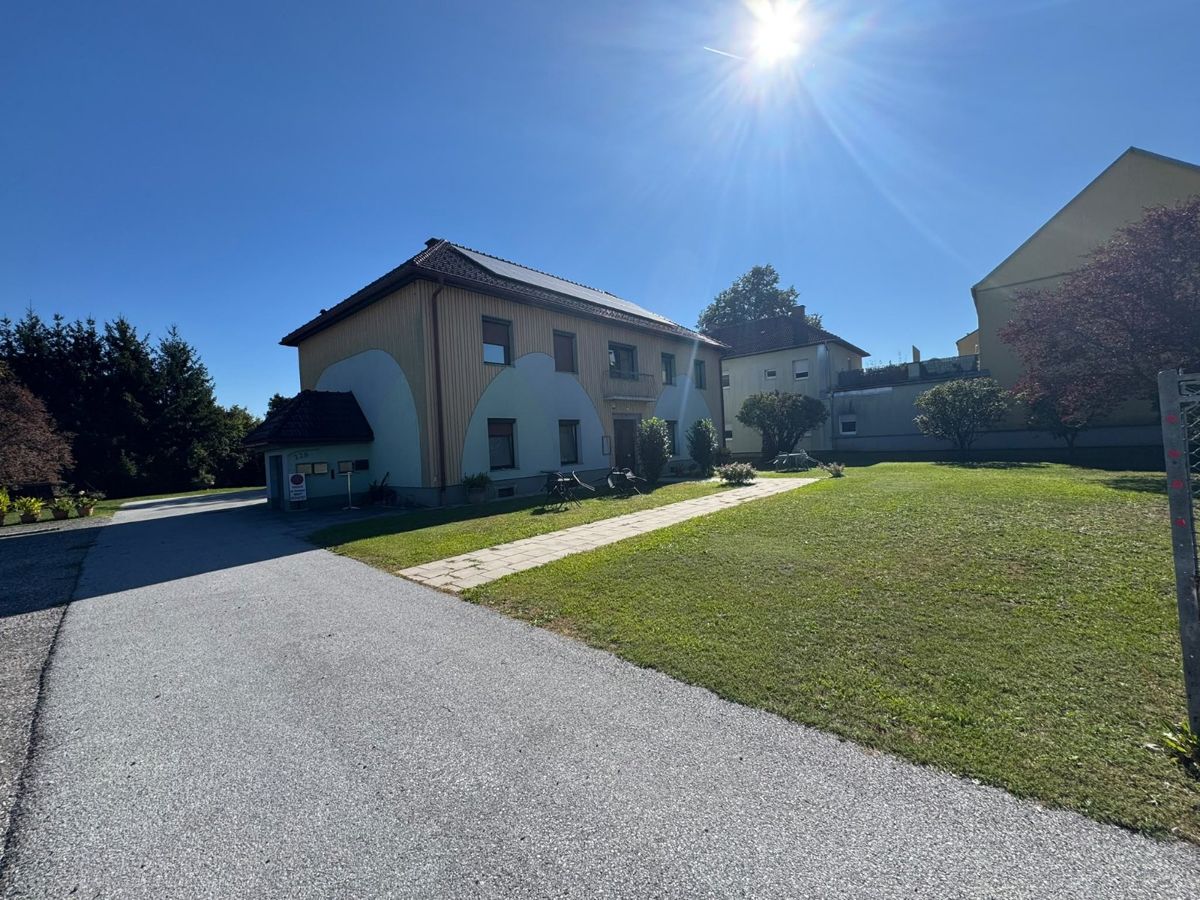 Haus mit Parkplatz und Garten bei Sonnenschein